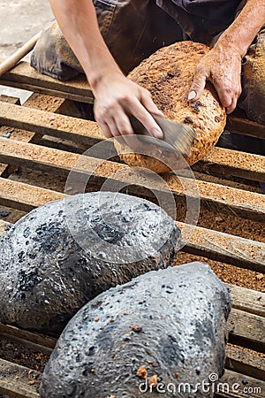 Making bread the traditional way - cleaning away the charred crust Stock Photo