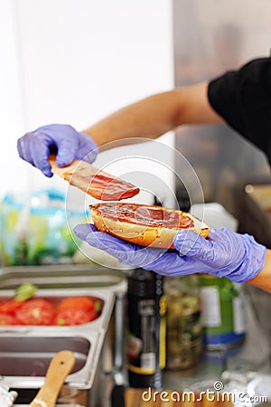 Making burgers. Preparing a hamburger in a protective gloves, in a food truck, in a fast food restaurant, close up. Stock Photo