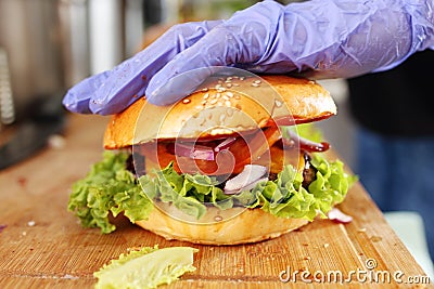 Making burgers. Preparing a hamburger in a protective gloves, in a food truck, in a fast food restaurant, close up. Stock Photo