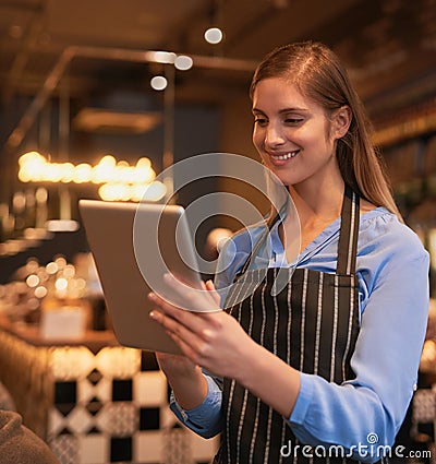 Making business simple. an attractive young woman using a digital tablet in her coffee shop. Stock Photo