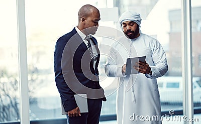 Making business success a collaborative effort. two businessmen using a digital tablet while having a discussion in a Stock Photo