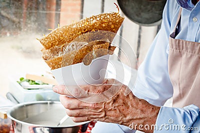 Making crepes pancakes at a food market. A hand is serving savoury crepes outdoors at a food stall Stock Photo