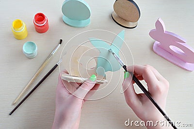 Making Easter decoration - easter eggs and bunny. Painting and coloring wooden toy of brushes and gouache. Creative process. Stock Photo
