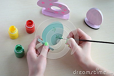 Making Easter decoration - easter eggs and bunny. Painting and coloring wooden toy of brushes and gouache. Creative process. Stock Photo