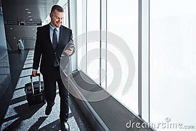 Making good use of the airport wifi. an executive businessman walking through an airport during a business trip. Stock Photo