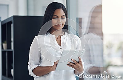 Making headway into her workday with digital technology. a young businesswoman using a digital tablet in an office. Stock Photo