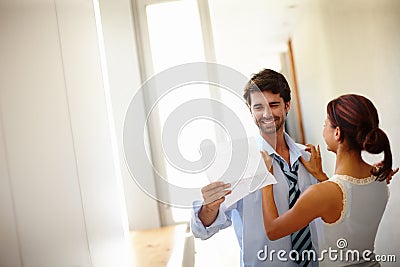 Making her man presentable. Handsome man reading while his wife dresses him. Stock Photo