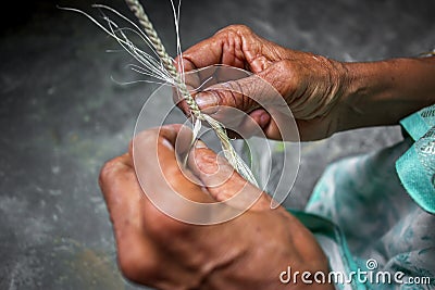 Making on his skinny hands a rope from the banana tree fiber Stock Photo