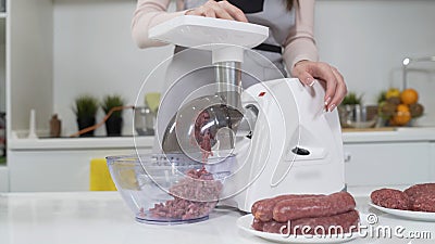 Making minced meat in electric meat grinder from fresh beef at home. Pile of chopped meat. Electric mincer machine with Stock Photo