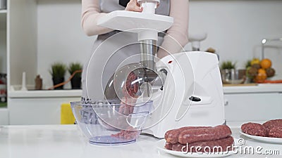 Making minced meat in electric meat grinder from fresh beef at home. Pile of chopped meat. Electric mincer machine with Stock Photo