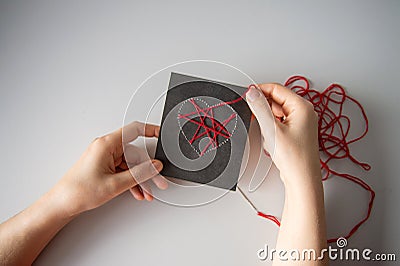 Making a postcard with a heart using thread printing on black cardboard Stock Photo