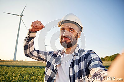 With notepad. Service engineer is on the field with windmills Stock Photo