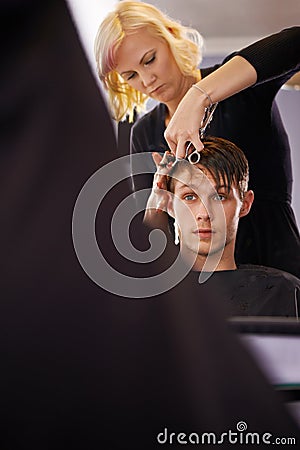 Making sure his hair looks sharp. A young man having his hair styled by a hairdresser. Stock Photo