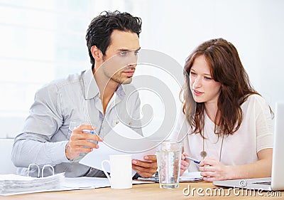 Making sure paper and online figures match. a two young design professionals sitting together and going over paperwork. Stock Photo