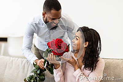 Young black man giving red roses to woman Stock Photo