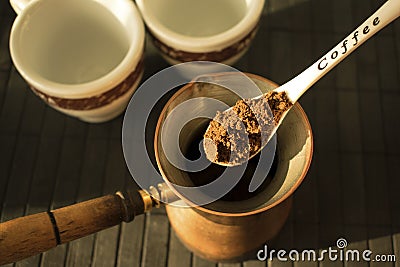 Making traditional greek / turkish black coffee on Turkish Coffee Pot. White spoon with the word coffee with ground coffee over t Stock Photo