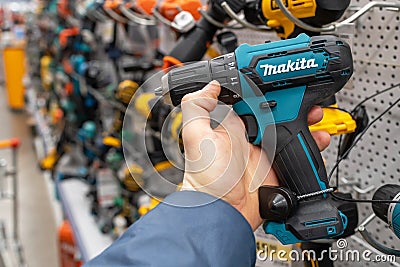 Makita cordless power drill. A man in a hardware store chooses a new drill or screwdriver. Minsk, Belarus, 2022 Editorial Stock Photo