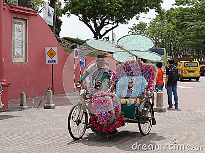 Malacca, Malaysia--February 2018: Wide shot of a colorful trishaw along the brick-paved Dutch Square in Melaka, Malaysia with Editorial Stock Photo