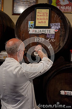 Malaga,Spain 04.04.2019: Bar tender pour the famous pajarete spanish wine from Sherry Barrels in the famous authentic Editorial Stock Photo