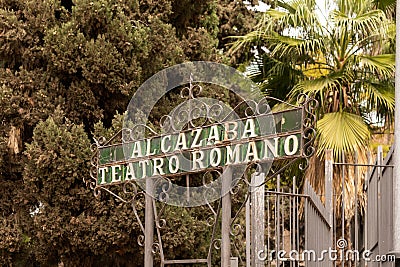 Malaga, Spain- 26-01-2024: Vintage metal sign 'ALCAZABA TEATRO ROMANO' among lush trees. The Roman Theatre is Editorial Stock Photo