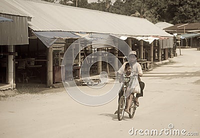 Poverty boys riding on a bicycle along a empty street Editorial Stock Photo