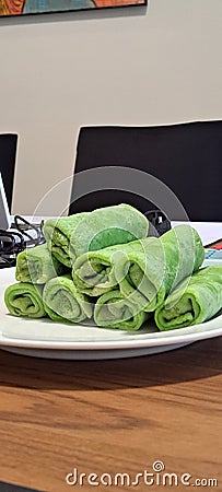 Malaysian delicacy called Kuih Ketayap. The green crepe filled with coconut. Stock Photo