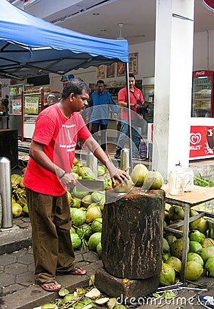 Malaysian man cutting young coconuts Editorial Stock Photo