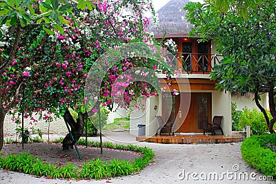 Maldives,Aug.2012. Colorful view to a exotic two-story round bungalow among blossom trees and palms Editorial Stock Photo