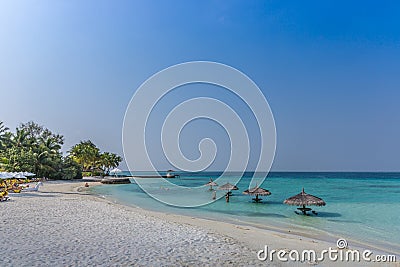 Maldives, Feb 3rd 2018 - Beach umbrellas at the shallow blue water with some divers enjoying the tropical weather of Maldives Stock Photo