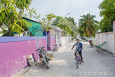 Maldivian boy riding bicycle on the street in the village at the tropical island Editorial Stock Photo