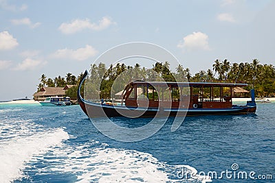Maldivian dhoni in front of the turquoise bay and island on Maldives Stock Photo