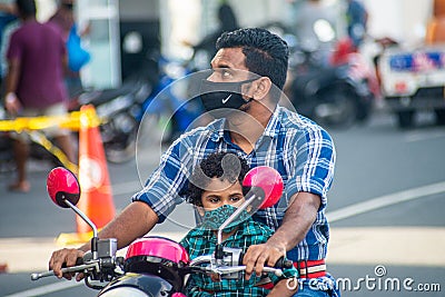 Maldivian man with child wearing masks while driving bike on the street during covid-19 Editorial Stock Photo