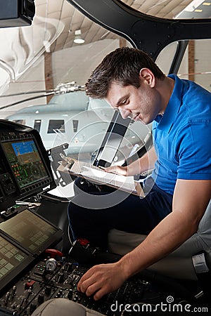 Male Aero Engineer With Clipboard Working In Helicopter Cockpit Stock Photo