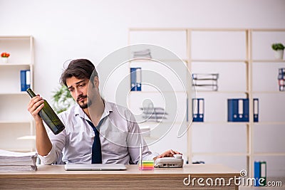 Young alcohol addicted employee sitting in the office Stock Photo