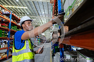 Male american african factory company employee scanning box checking number of products on goods shelves with tablet in warehouse Stock Photo