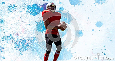 Male american football player holding ball against abstract splattered blue background Stock Photo