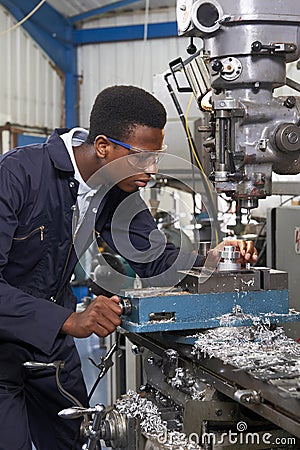 Male Apprentice Engineer Working On Drill In Factory Stock Photo