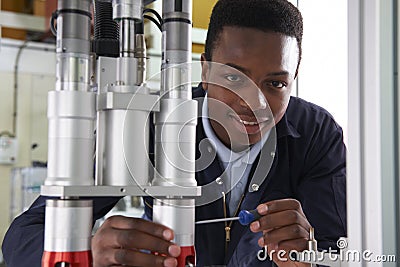 Male Apprentice Engineer Working On Machine In Factory Stock Photo