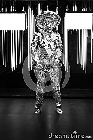 a male artist in a mirrored suit and hat with an electric guitar on a dark background Editorial Stock Photo