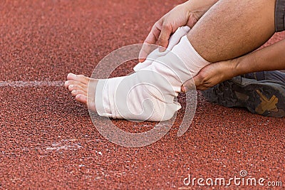 Male athlete applying compression bandage onto ankle injury of a football player, Editorial Stock Photo