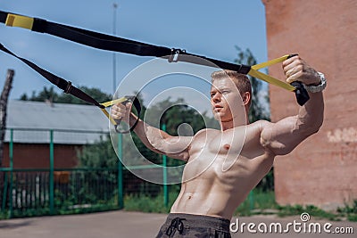 Male athlete close-up, trains nature city, summer trx training, Feel your strength and balance, motivation, tanned skin Stock Photo