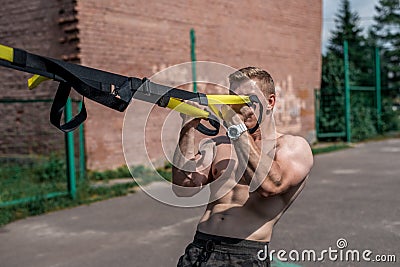 Male athlete is an excellent training, city in summer, trx training, feel your strength and balance, motivation, tanned Stock Photo