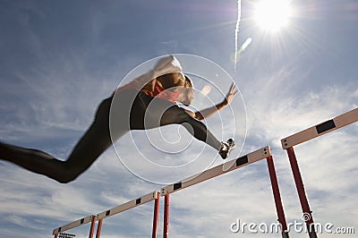 Male Athlete Jumping Hurdle Stock Photo