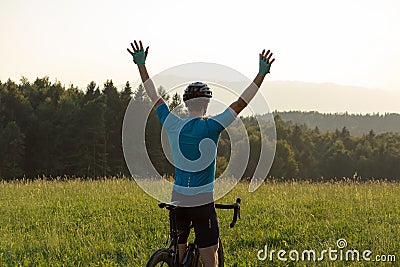 Male cyclist riding a bike with arms raised, in a victory pose Stock Photo