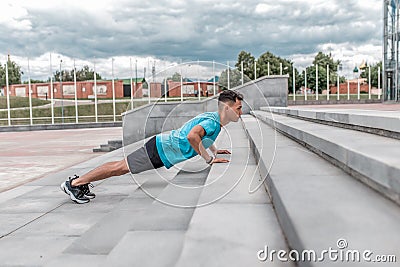 Male athlete is pushing up from concrete steps in summer city. Fitness motivation youth lifestyle. Free space for copy Stock Photo