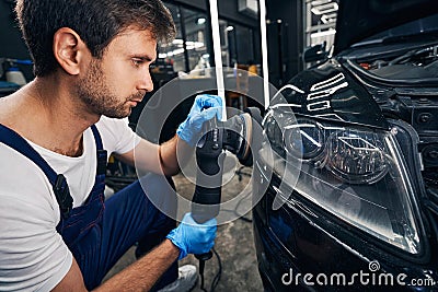 Male automotive repairman polishing car front lights Stock Photo