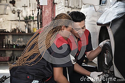 Male automotive supervisor trained mechanic to screw car wheel nuts at garage. Stock Photo