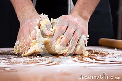 Male baker kneading dough on flour covered table Stock Photo