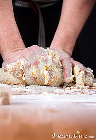 Male baker kneading dough on flour covered table Stock Photo