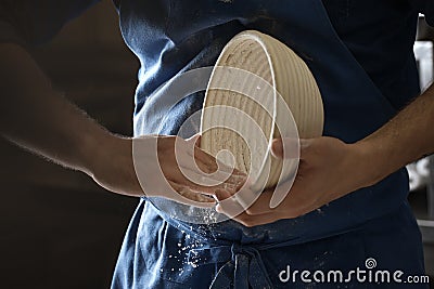 Male baker lightly flouring proofing basket for home made sourdough bread. Stock Photo